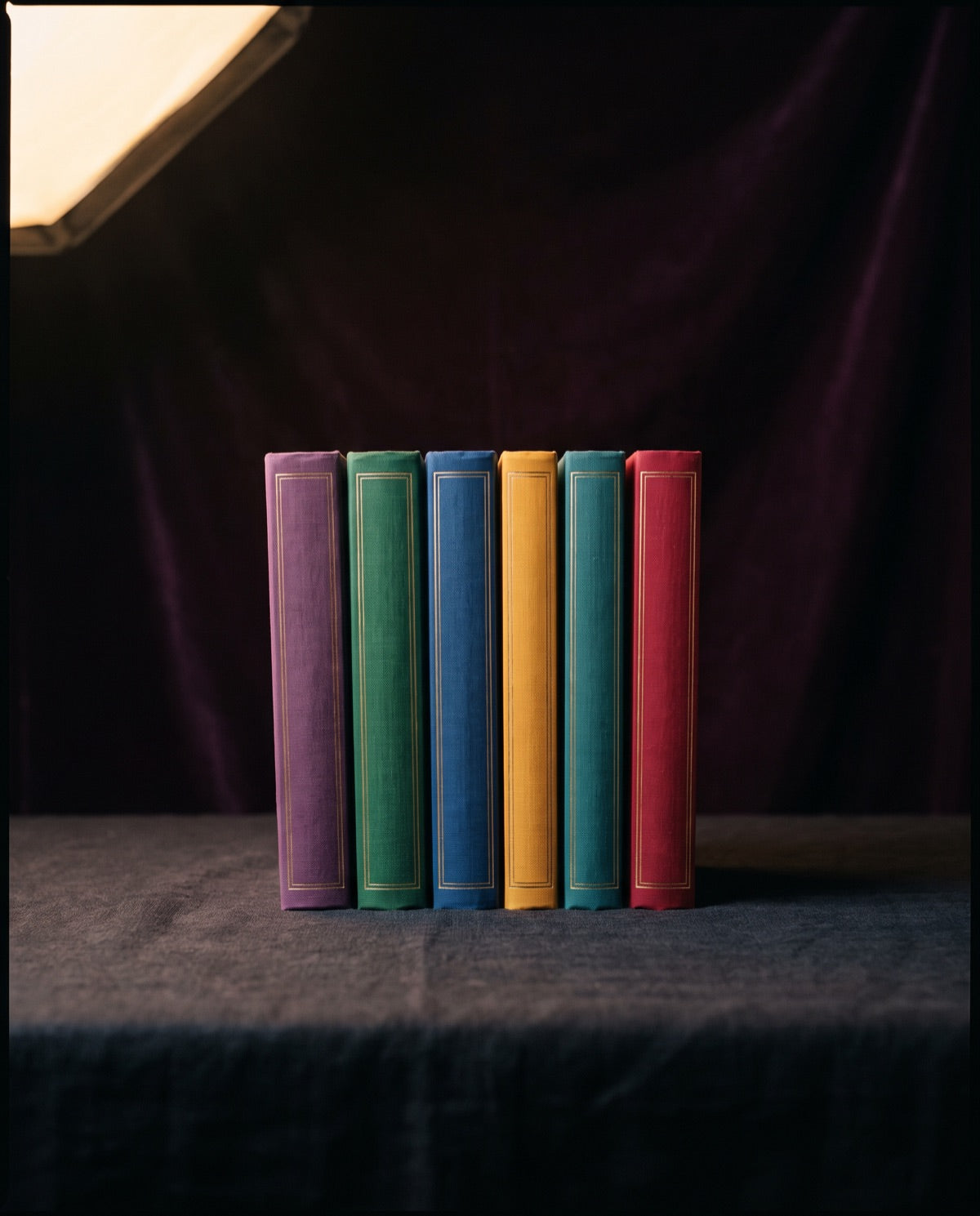 The six volumes of the Codex standing together on dark linen
